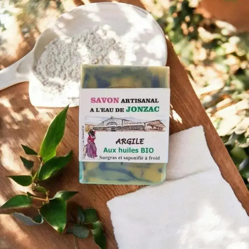 savon artisanal argile saponifié à froid à l’eau de Jonzac posé sur planche bois avec bol de poudre d’argile