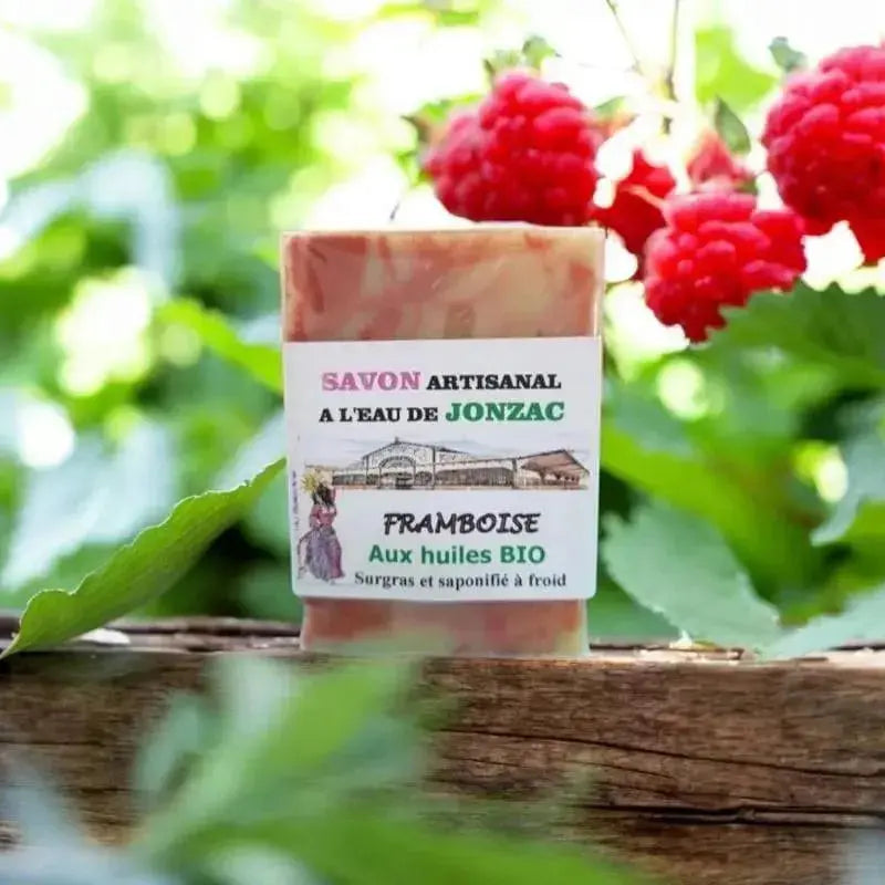 savon artisanal framboise saponifié à froid à l’eau de Jonzac posé sur bois avec framboises fraîches