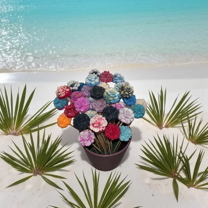Bouquet de petits œillets en cire artisanale, fleurs colorées dans un vase posé sur le sable au bord de la mer turquoise – Lulu Baladine