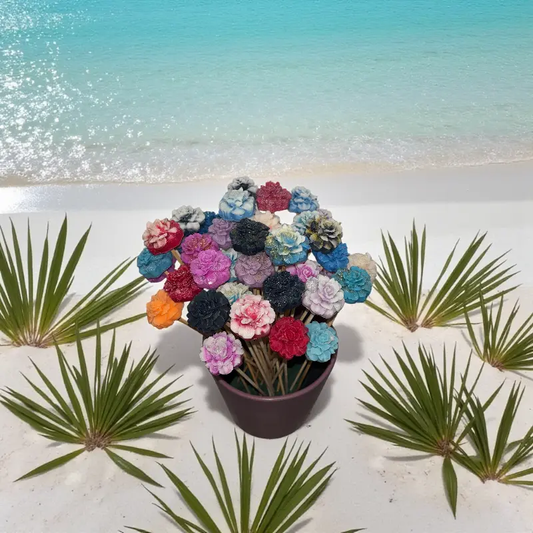 Bouquet de petits œillets en cire artisanale, fleurs colorées dans un vase posé sur le sable au bord de la mer turquoise – Lulu Baladine