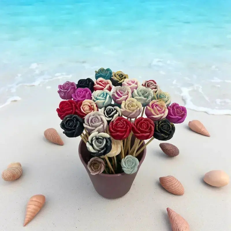 Bouquet de petites roses multicolores Lulu Baladine posé sur le sable au bord de la mer, entouré de coquillages.