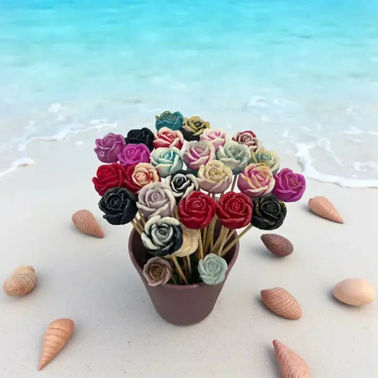 Bouquet de petites roses multicolores Lulu Baladine posé sur le sable au bord de la mer, entouré de coquillages.