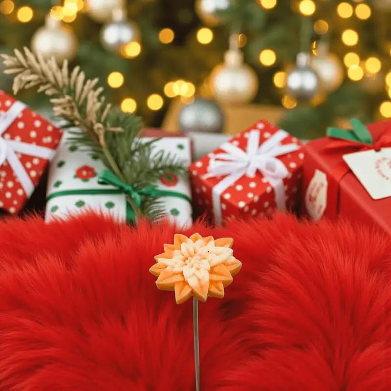 Étoile de Noël orange et crème en cire artisanale, fleur décorative festive parmi des cadeaux de Noël – Lulu Baladine