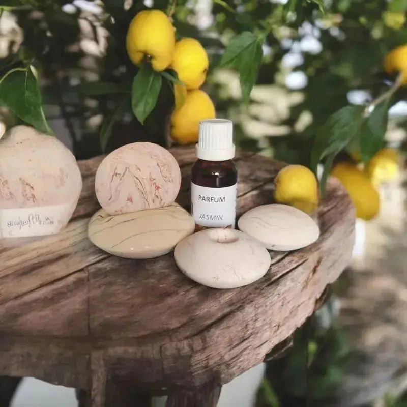 fiole ambrée d’extrait de parfum jasmin posée sur bois, citrons en arrière-plan