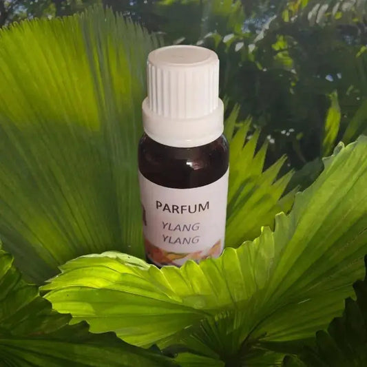 gros plan sur la fiole ambrée d’extrait parfum ylang ylang sur fond vert tropical