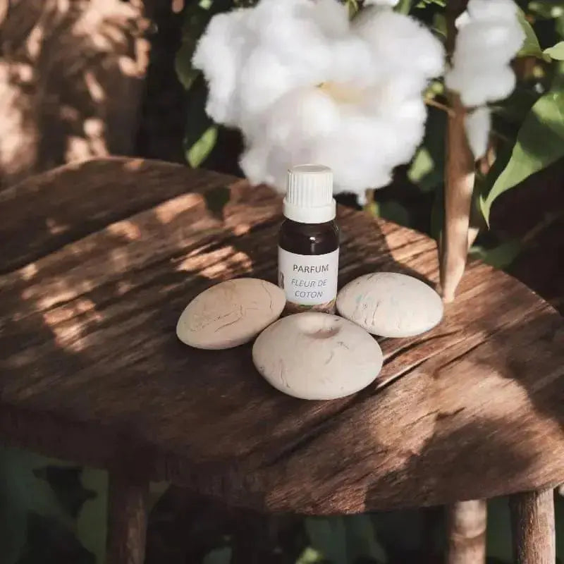 fiole en verre ambré, étiquette “fleur de coton”, extrait de parfum sur table avec Aroma a parfumé