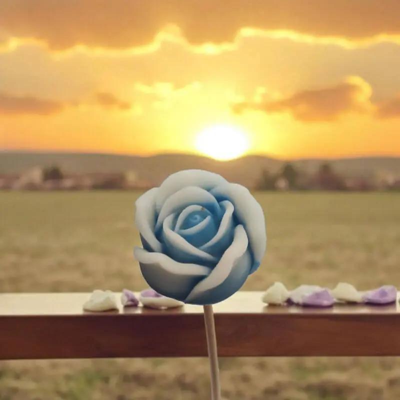 Petite rose bleue bordée de blanc en cire de soja naturelle devant un coucher de soleil — fleur parfumée artisanale à acheter, décoration poétique et cadeau symbolique.