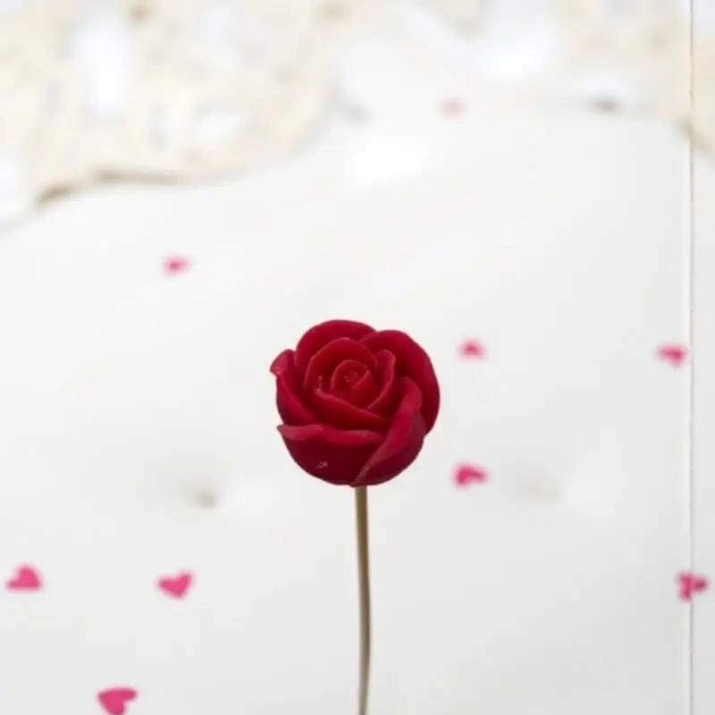 Petite rose rouge Lulu Baladine sur une table blanche lumineuse avec des coeur rose.