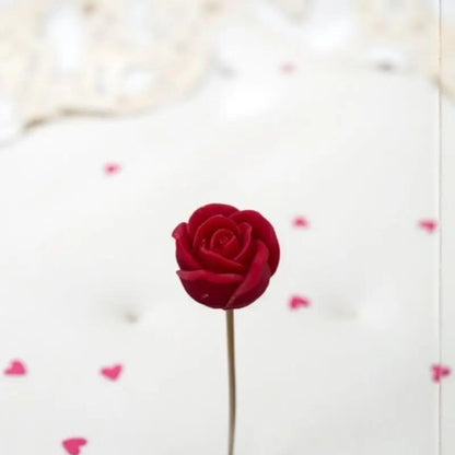 Petite rose rouge Lulu Baladine sur une table blanche lumineuse avec des coeur rose.