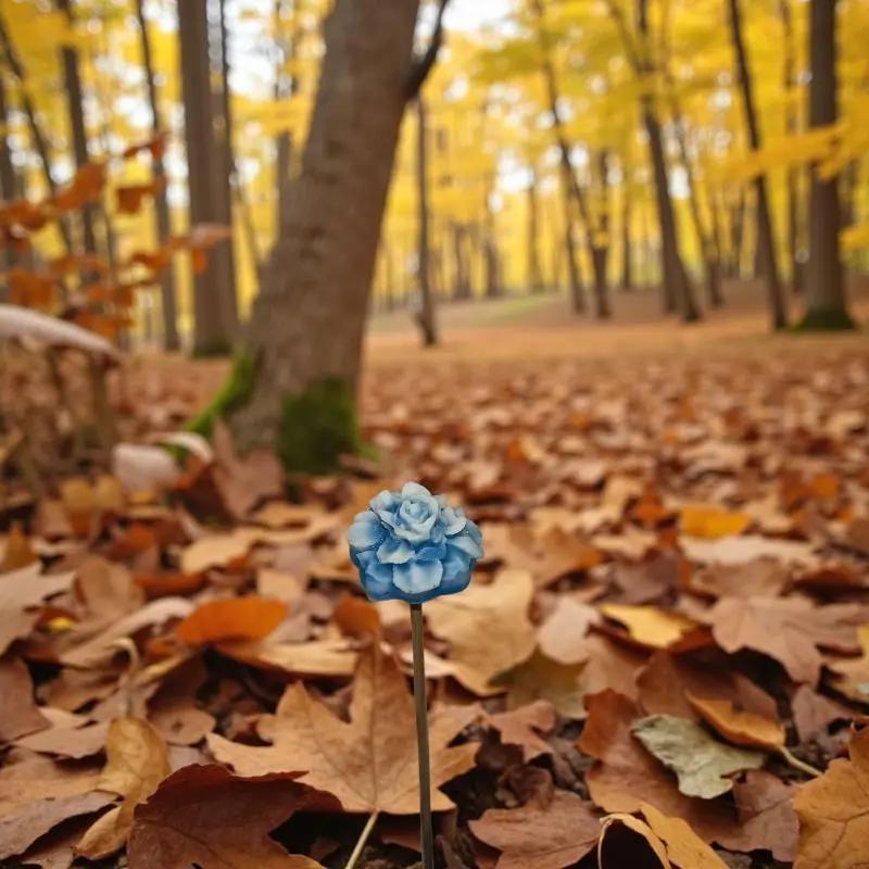 Petite fleur bleue décorative plantée au sol, mise en valeur dans une forêt d’automne couverte de feuilles orangées — accessoire floral original pour décoration intérieure ou extérieure