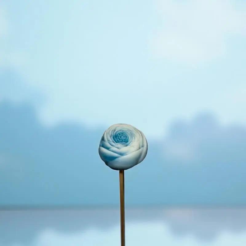 Petite renoncule bordée turquoise en cire artisanale, fleur décorative douce et apaisante sur fond bleu ciel – Lulu Baladine