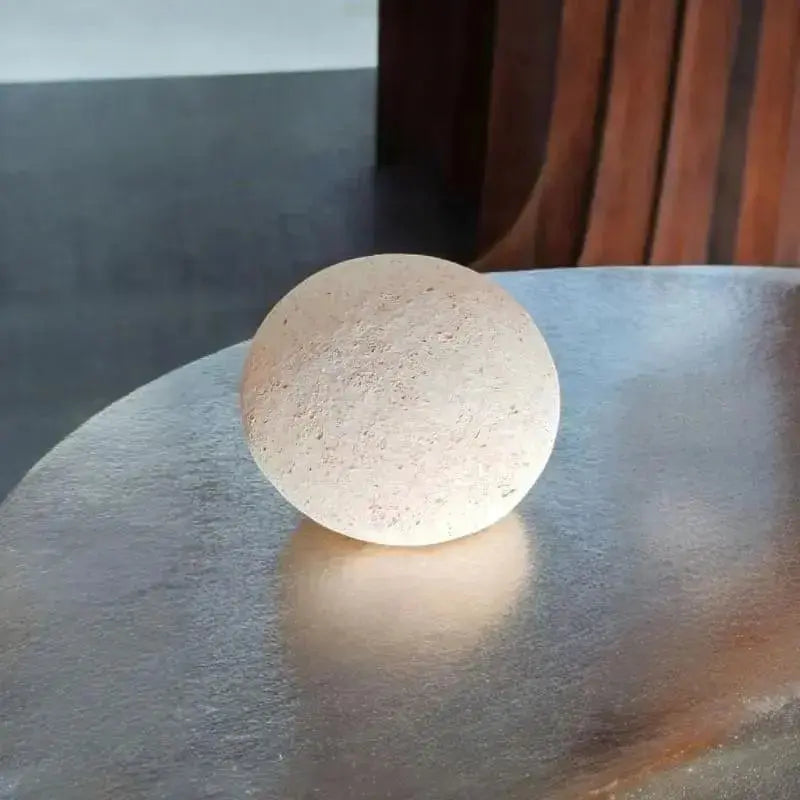 Pierre visage posée sur une table en metal avec un décors de bois dernière 