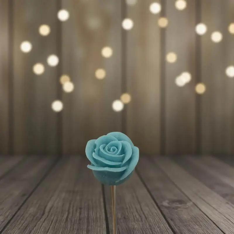 Rose turquoise en cire artisanale, fleur décorative posée sur fond en bois et lumières dorées – Lulu Baladine