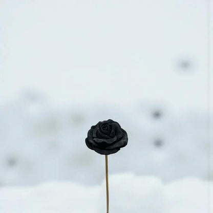 Rose moyenne noire en cire artisanale, fleur décorative chic et minimaliste sur fond neigeux – Lulu Baladine