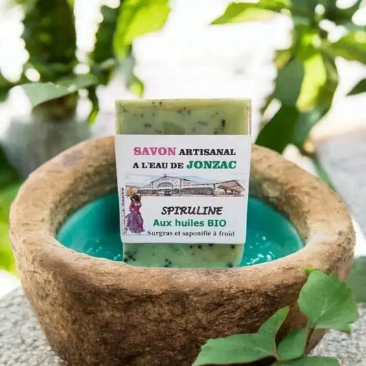savon artisanal spiruline saponifié à froid à l’eau de Jonzac posé sur pierre avec eau turquoise