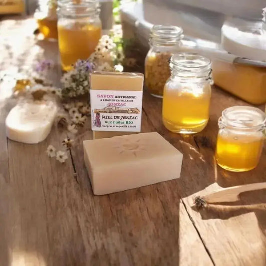 savon artisanal miel de Jonzac saponifié à froid posé sur planche bois avec pots de miel et fleurs sèches