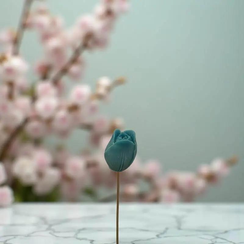 Tulipe turquoise en cire artisanale, fleur décorative artisanale devant des fleurs de cerisier – Lulu Baladine