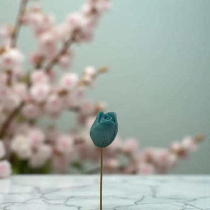 Tulipe turquoise en cire artisanale, fleur décorative artisanale devant des fleurs de cerisier – Lulu Baladine